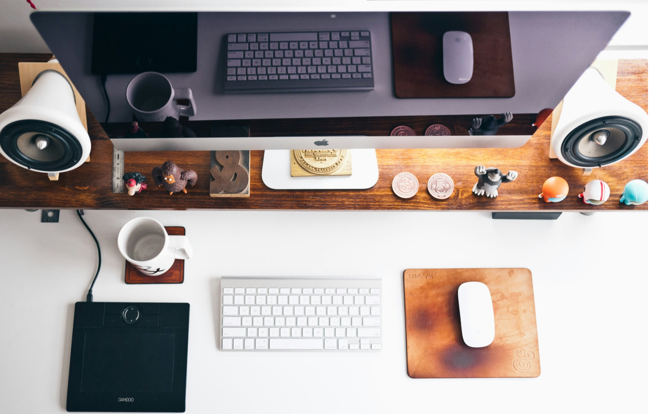 A top-down view of a well-organized designer's workspace featuring a desktop computer, keyboard, graphics tablet, and various decorative items. The setup reflects a professional environment ideal for branding, website design, and lead generation projects.